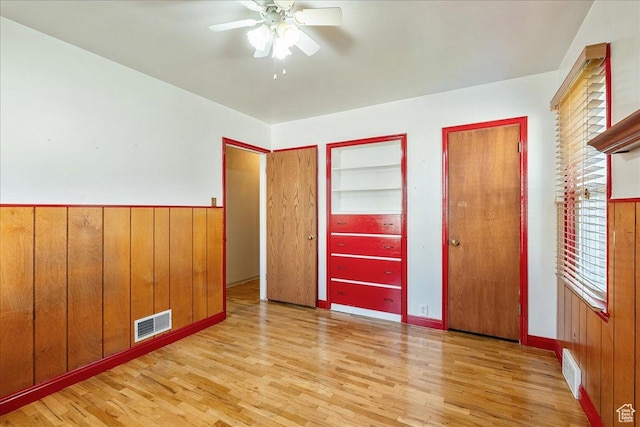 458 E 8800 S, Sandy, UT 84070 - unfurnished bedroom with light wood-style floors, multiple closets, wooden walls, wainscoting, and a ceiling fan