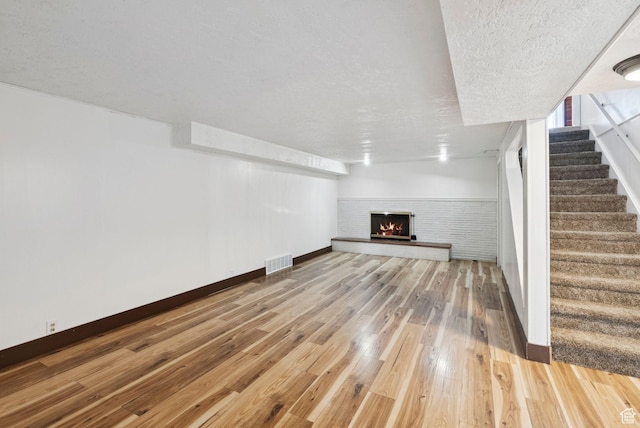 2999 N 300 E, North Ogden, UT 84414 - unfurnished living room featuring light wood-type flooring, stairs, a fireplace, and a textured ceiling