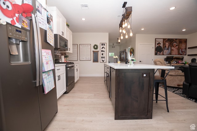 365 N 800 E, Beaver, UT 84713 - kitchen featuring appliances with stainless steel finishes, a kitchen breakfast bar, white cabinets, light wood-style flooring, and an island with sink