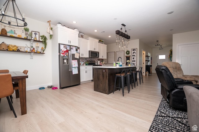 365 N 800 E, Beaver, UT 84713 - kitchen featuring stainless steel appliances, open floor plan, a kitchen bar, light wood-style flooring, and light countertops