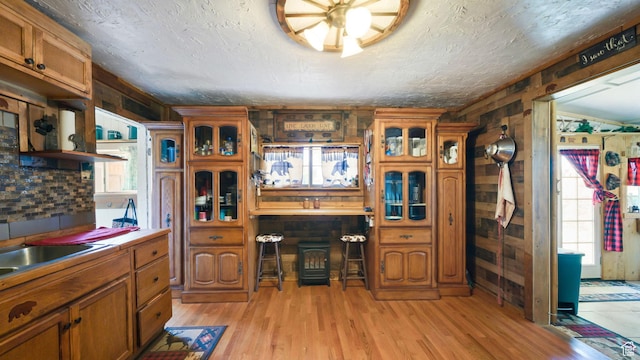 180 N State St, Sigurd, UT 84657 - kitchen with brown cabinets, light wood-style floors, wood walls, glass insert cabinets, and light countertops