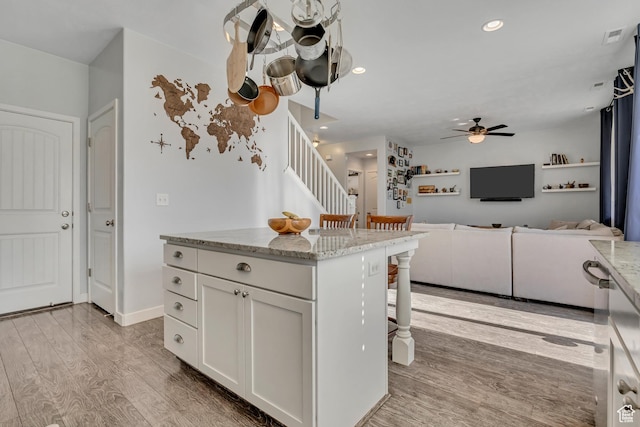 1046 W Stonehaven Dr, North Salt Lake, UT 84054 - kitchen featuring a ceiling fan, a breakfast bar, light wood-type flooring, white cabinetry, and light stone counters