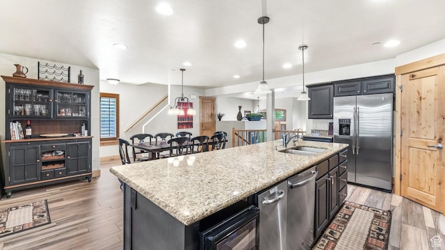 5541 N Slalom Way, Park City, UT 84098 - kitchen featuring appliances with stainless steel finishes, a kitchen island with sink, light wood finished floors, light stone counters, and recessed lighting