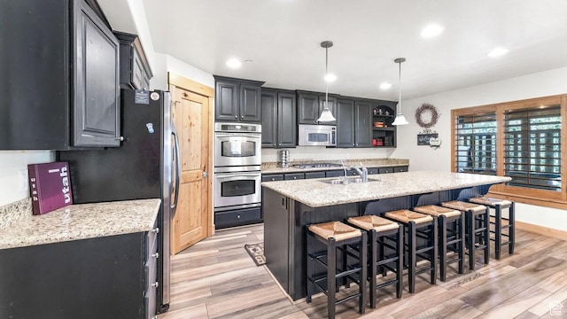 5541 N Slalom Way, Park City, UT 84098 - kitchen featuring appliances with stainless steel finishes, light wood finished floors, a kitchen breakfast bar, an island with sink, and recessed lighting