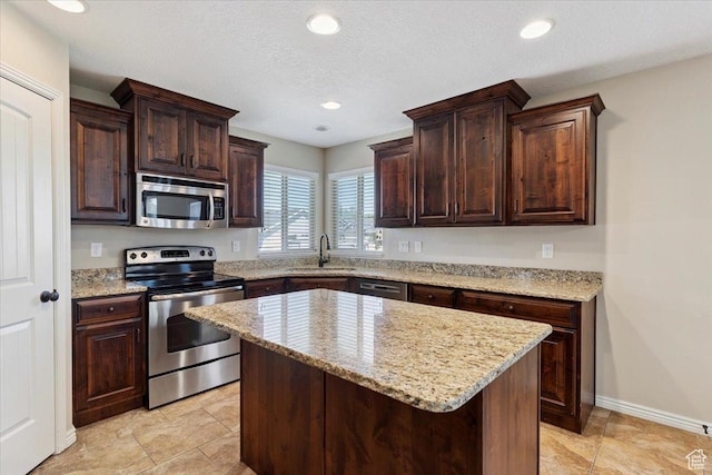 5464 S 3200 W, Roy, UT 84067 - kitchen with appliances with stainless steel finishes, dark brown cabinetry, a kitchen island, light stone counters, and recessed lighting