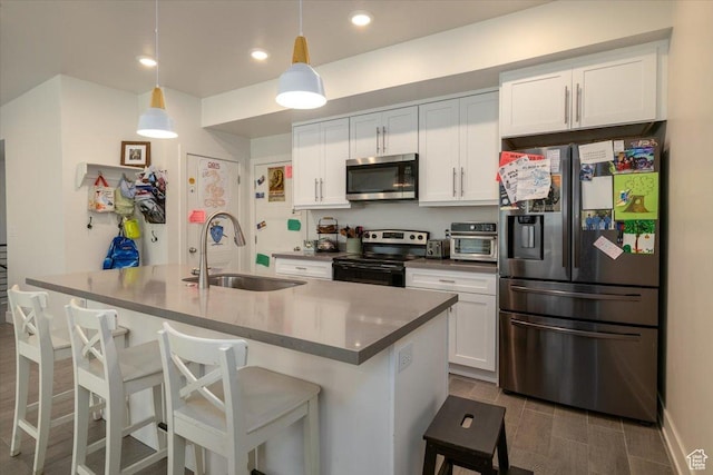 2049 N Harvest Village Ln, Saratoga Springs, UT 84045 - kitchen featuring appliances with stainless steel finishes, white cabinetry, a breakfast bar, an island with sink, and hanging light fixtures