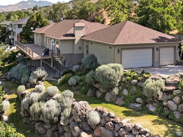 2960 E Oak Park Ln S, Holladay, UT 84117 - view of front facade featuring a garage, a shingled roof, a deck with mountain view, stucco siding, and driveway