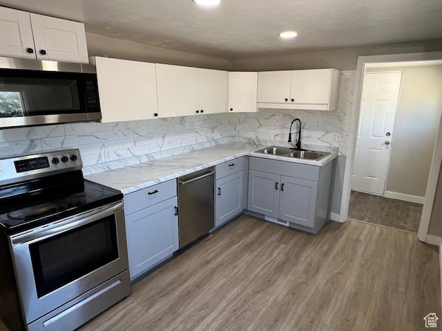 9173 S 1300 W, West Jordan, UT 84088 - kitchen featuring stainless steel appliances, gray cabinets, light wood finished floors, tasteful backsplash, and white cabinetry