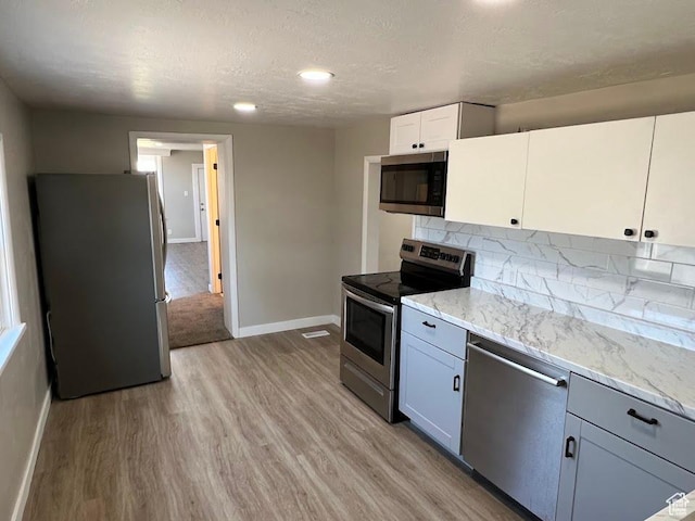 9173 S 1300 W, West Jordan, UT 84088 - kitchen featuring appliances with stainless steel finishes, light wood-type flooring, tasteful backsplash, light stone counters, and a textured ceiling