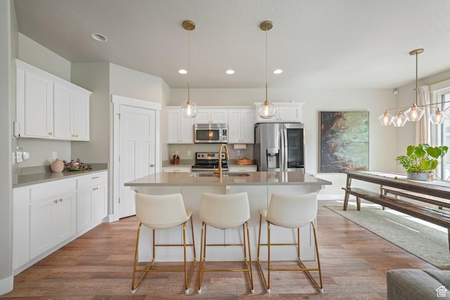 933 S 2100 W, Orem, UT 84059 - kitchen featuring appliances with stainless steel finishes, a kitchen island with sink, light wood finished floors, white cabinetry, and recessed lighting