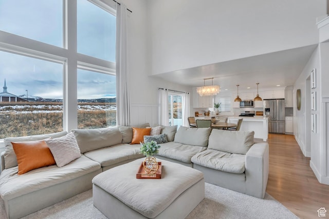 1769 W Stone Gate Dr, Saratoga Springs, UT 84045 - living room with light wood-style floors, a high ceiling, a wainscoted wall, and a chandelier