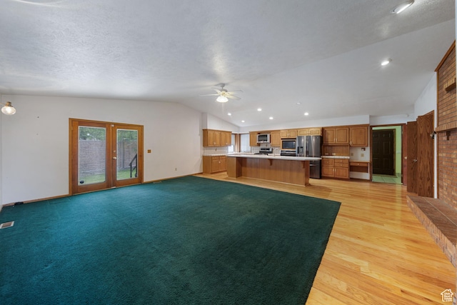 5350 S Jordan Canal Rd, Salt Lake City, UT 84129 - unfurnished living room featuring vaulted ceiling, a ceiling fan, light wood-style floors, a textured ceiling, and french doors