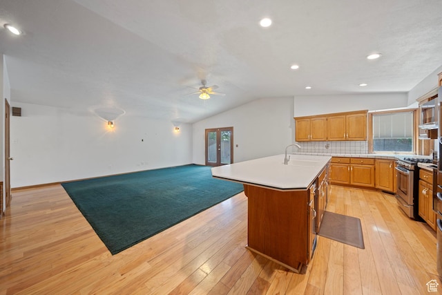 5350 S Jordan Canal Rd, Salt Lake City, UT 84129 - kitchen featuring gas stove, ceiling fan, an island with sink, open floor plan, and decorative backsplash