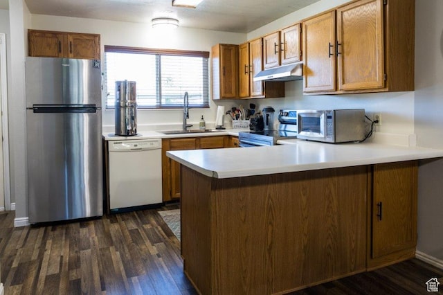 63 S 100 W Unit 17, American Fork, UT 84003 - kitchen with stainless steel appliances, under cabinet range hood, a peninsula, brown cabinetry, and dark wood-style floors