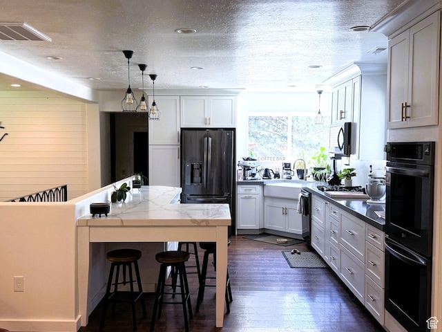 1990 E 400 N, Mapleton, UT 84664 - kitchen with black appliances, a breakfast bar, decorative light fixtures, dark wood-style flooring, and a textured ceiling