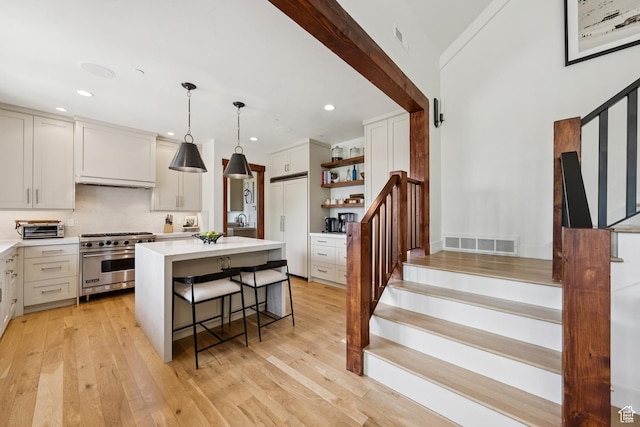 9388 Dye Cabins Dr, Park City, UT 84098 - kitchen featuring premium appliances, open shelves, light countertops, a breakfast bar, and light wood-style flooring
