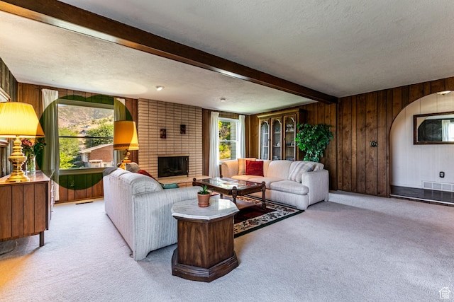 342 E State St, Farmington, UT 84025 - living room featuring light colored carpet, a textured ceiling, beam ceiling, wood walls, and a brick fireplace