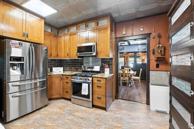 367 W 400 N, Malad City, ID 83252 - kitchen with stainless steel appliances, brown cabinetry, an ornate ceiling, light stone counters, and tasteful backsplash