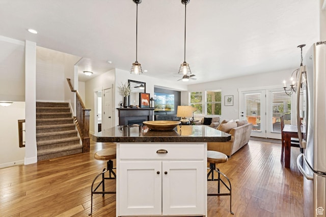 693 S Silver Leaf Dr W, Mapleton, UT 84664 - kitchen featuring a breakfast bar, open floor plan, white cabinets, light wood-type flooring, and freestanding refrigerator
