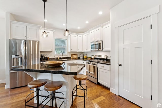 693 S Silver Leaf Dr W, Mapleton, UT 84664 - kitchen featuring appliances with stainless steel finishes, a kitchen bar, white cabinets, dark countertops, and light wood finished floors