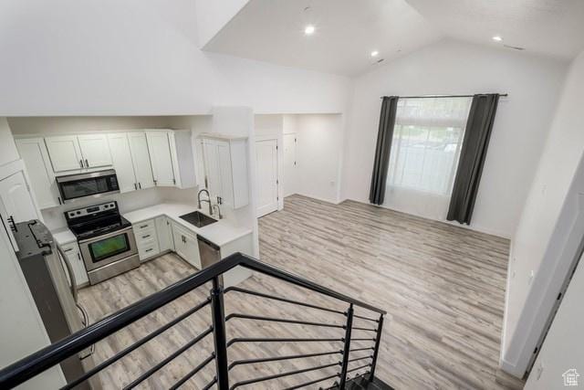 63 E Bridle Villa Dr, Draper, UT 84020 - kitchen with stainless steel appliances, light wood-style flooring, lofted ceiling, light countertops, and white cabinets