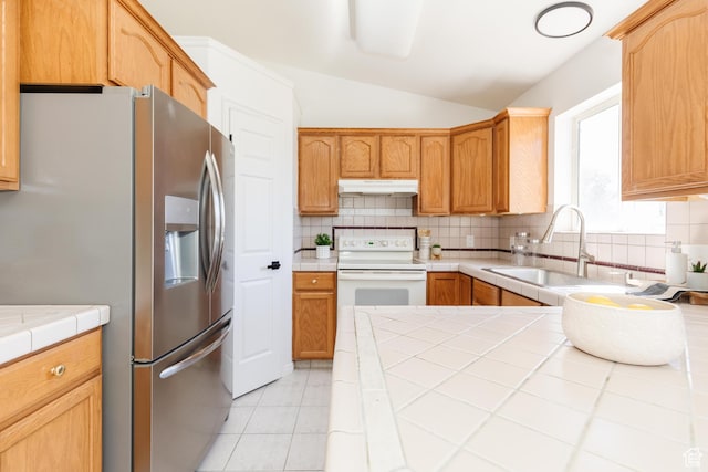 431 S Oakwood Dr W, Logan, UT 84321 - kitchen featuring stainless steel fridge, white electric stove, vaulted ceiling, under cabinet range hood, and decorative backsplash
