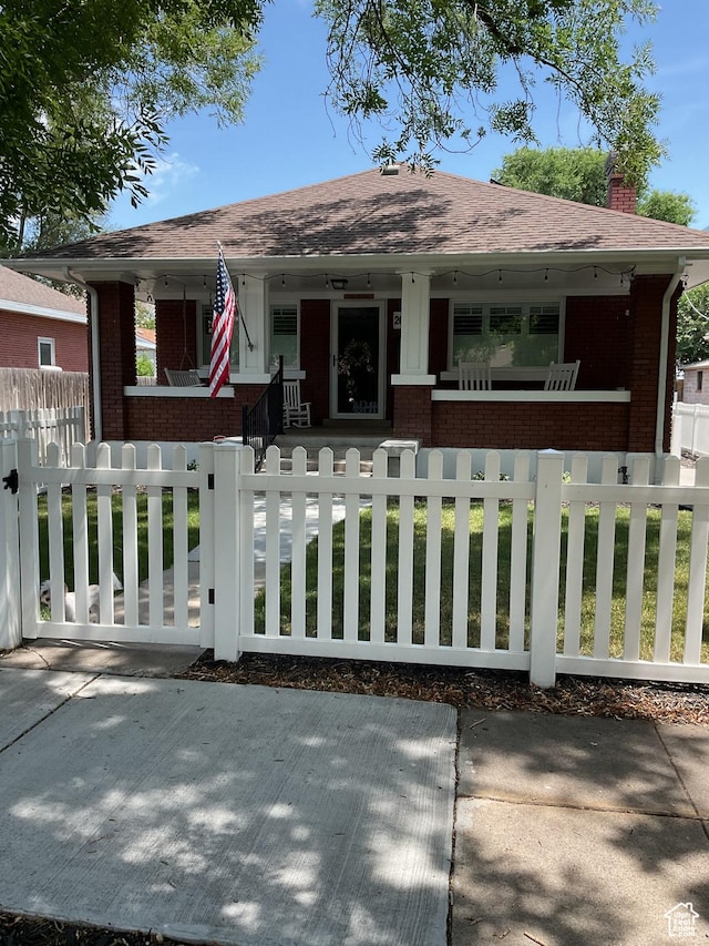 2044 Madison Ave, Ogden, UT 84401 - bungalow with covered porch, brick siding, a chimney, and a fenced front yard