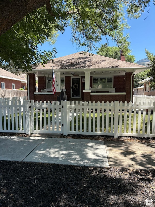 2044 Madison Ave, Ogden, UT 84401 - bungalow-style house featuring covered porch, brick siding, a chimney, and a fenced front yard