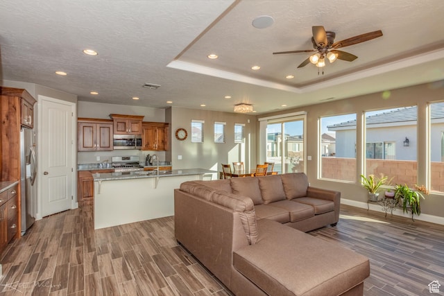 3429 W 175 N, Hurricane, UT 84737 - living area featuring wood finished floors, a tray ceiling, ceiling fan, recessed lighting, and a textured ceiling