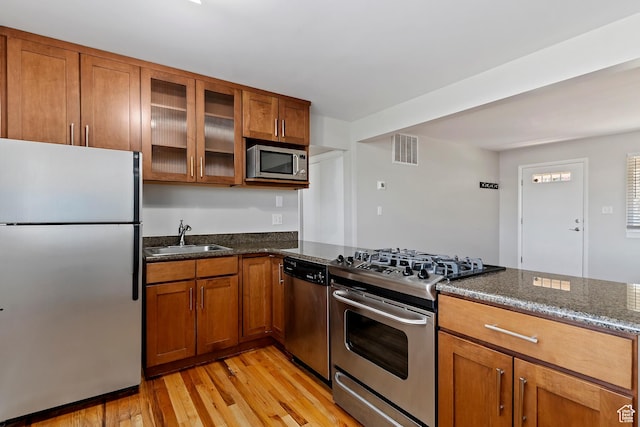 650 N 300 W Unit 229, Salt Lake City, UT 84103 - kitchen with appliances with stainless steel finishes, brown cabinets, dark stone counters, and light wood-style floors