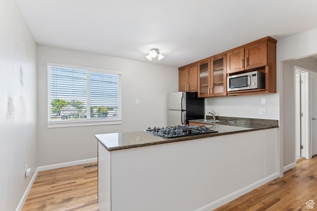 650 N 300 W Unit 229, Salt Lake City, UT 84103 - kitchen featuring stainless steel microwave, black gas cooktop, freestanding refrigerator, brown cabinetry, and light wood-style floors