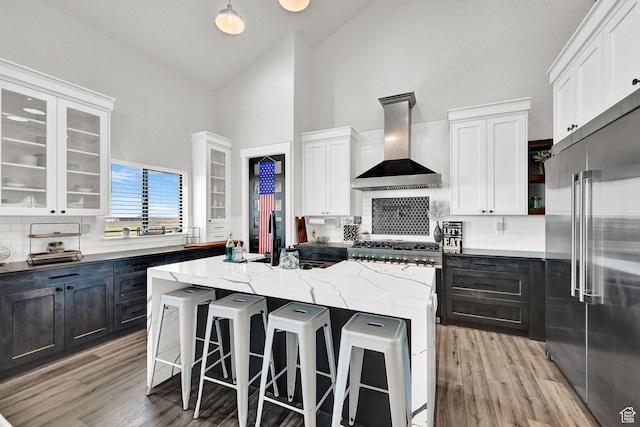 2673 S 4950 W, Taylor, UT 84401 - kitchen featuring wall chimney range hood, built in refrigerator, high vaulted ceiling, white cabinets, and a center island