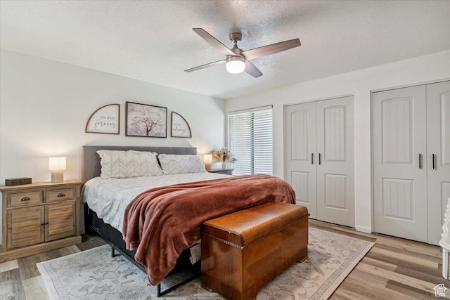 5659 Woodshire Ct, South Ogden, UT 84403 - bedroom with two closets, light wood-type flooring, a textured ceiling, and a ceiling fan