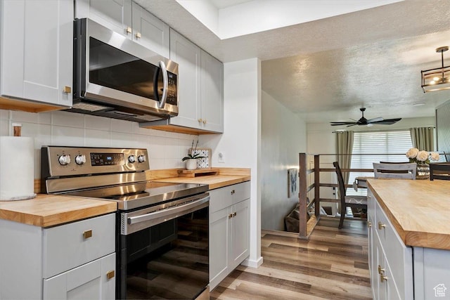 5659 Woodshire Ct, South Ogden, UT 84403 - kitchen with wood counters, stainless steel appliances, light wood-type flooring, tasteful backsplash, and a textured ceiling