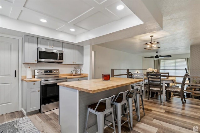 5659 Woodshire Ct, South Ogden, UT 84403 - kitchen featuring stainless steel appliances, butcher block countertops, coffered ceiling, light wood-style flooring, and a ceiling fan