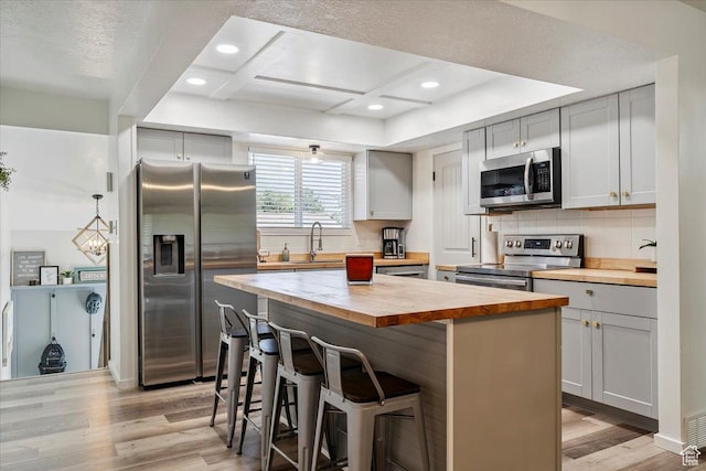 5659 Woodshire Ct, South Ogden, UT 84403 - kitchen featuring butcher block countertops, stainless steel appliances, light wood finished floors, a kitchen breakfast bar, and tasteful backsplash
