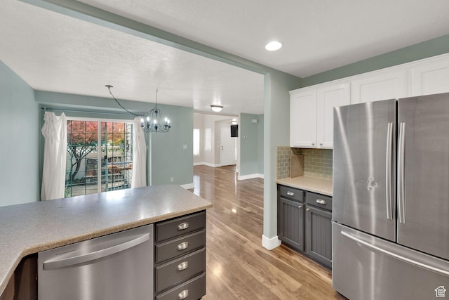 797 E 10 S, American Fork, UT 84003 - kitchen featuring appliances with stainless steel finishes, light wood-type flooring, white cabinetry, a chandelier, and backsplash