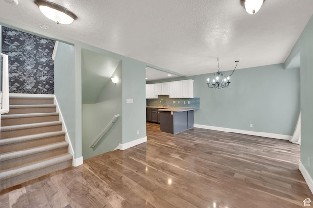 797 E 10 S, American Fork, UT 84003 - unfurnished living room with wood finished floors, a chandelier, a textured ceiling, and stairs