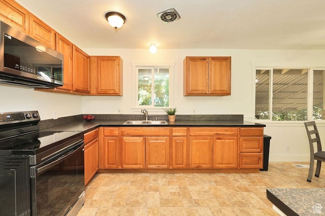 3165 S Jackson Ave, Ogden, UT 84403 - kitchen featuring black range with electric cooktop, stainless steel microwave, dark countertops, and brown cabinetry