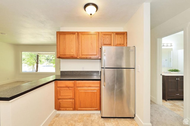 3165 S Jackson Ave, Ogden, UT 84403 - kitchen featuring freestanding refrigerator, dark countertops, and brown cabinetry