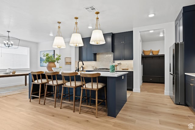 3353 W Bonita Unit 23, Hurricane, UT 84737 - kitchen with stainless steel refrigerator with ice dispenser, light countertops, tasteful backsplash, light wood-type flooring, and a kitchen island with sink