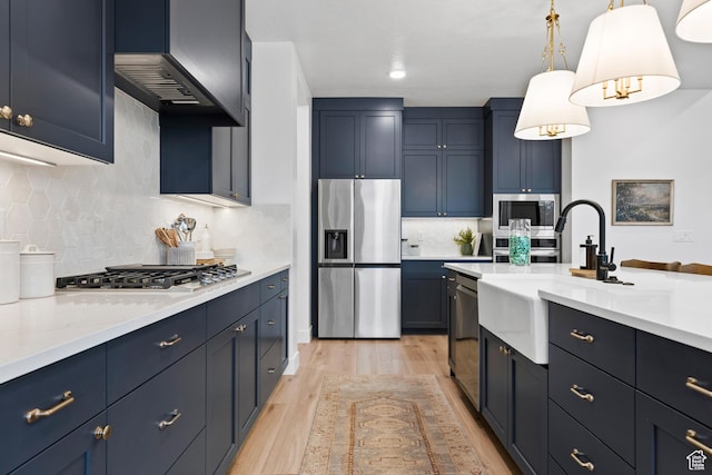 3353 W Bonita Unit 23, Hurricane, UT 84737 - kitchen with stainless steel appliances, light wood-type flooring, tasteful backsplash, exhaust hood, and hanging light fixtures