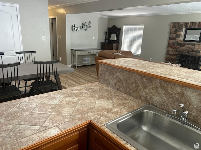2537 S Taylor Ave E, Ogden, UT 84401 - kitchen featuring crown molding, wood finished floors, a stone fireplace, open floor plan, and backsplash