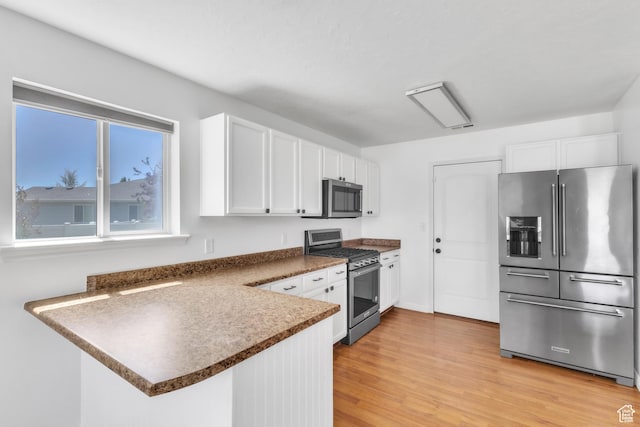 985 W 2675 S, Nibley, UT 84321 - kitchen featuring stainless steel appliances, white cabinets, dark countertops, light wood-style floors, and a peninsula