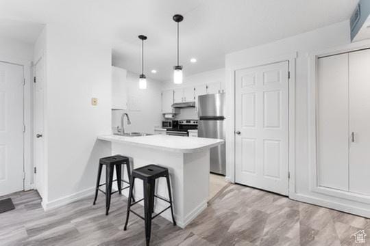 1196 E Waterside Cv S Unit 11, Cottonwood Heights, UT 84047 - kitchen featuring range with electric cooktop, freestanding refrigerator, a breakfast bar, light countertops, and a peninsula