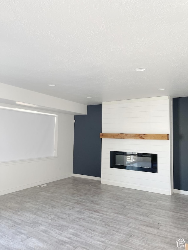 63 E Rose Way, Vineyard, UT 84059 - unfurnished living room with a fireplace, wood finished floors, a textured ceiling, and recessed lighting