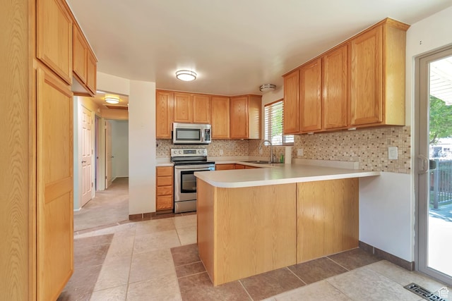1241 W 4505 S, Taylorsville, UT 84123 - kitchen featuring appliances with stainless steel finishes, a peninsula, light countertops, tasteful backsplash, and light tile patterned floors