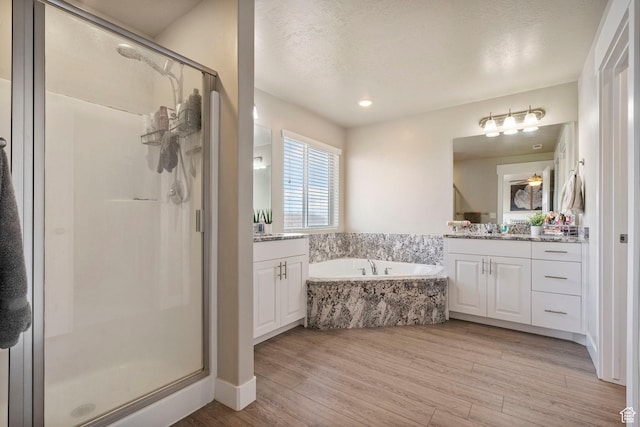 3323 E Gibraltar Ave, Eagle Mountain, UT 84005 - bathroom with a stall shower, two vanities, wood finished floors, a bath, and a textured ceiling
