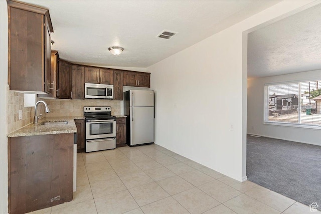 330 W 750 N, Clearfield, UT 84015 - kitchen with appliances with stainless steel finishes, tasteful backsplash, dark brown cabinets, light stone countertops, and light tile patterned flooring