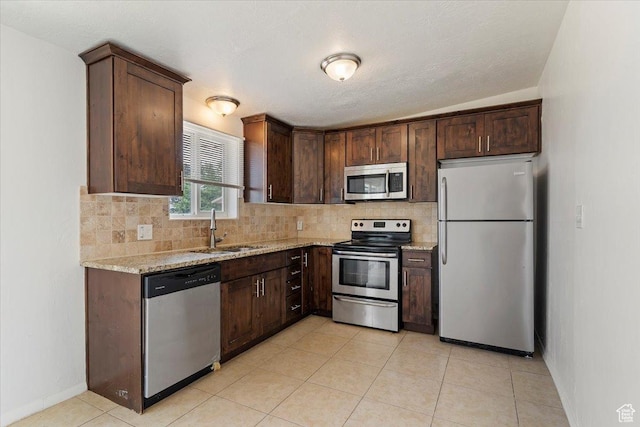 330 W 750 N, Clearfield, UT 84015 - kitchen featuring appliances with stainless steel finishes, decorative backsplash, light stone countertops, dark brown cabinets, and light tile patterned flooring
